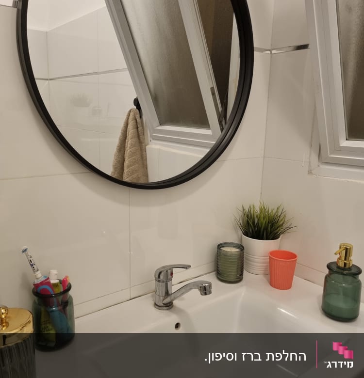 כיור עם ברז כסוף ומראה עגולה בחדר אמבטיה